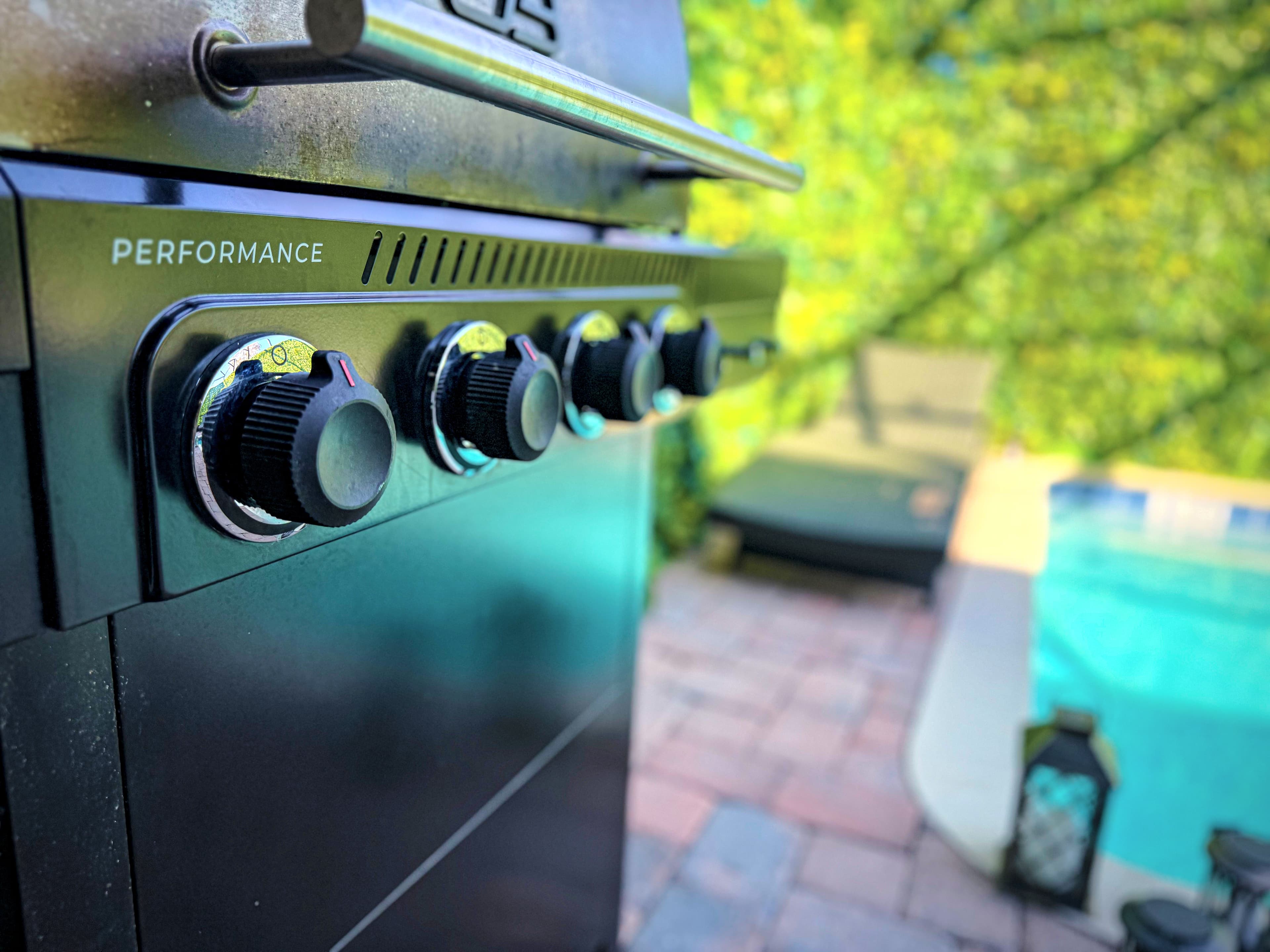 Char-Broil Performance BBQ grill steps from the pool, knobs gleaming in the afte