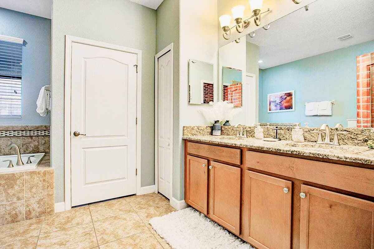Dual-sink granite vanity, a deep soaking tub with brushed-bronze fixtures, and s