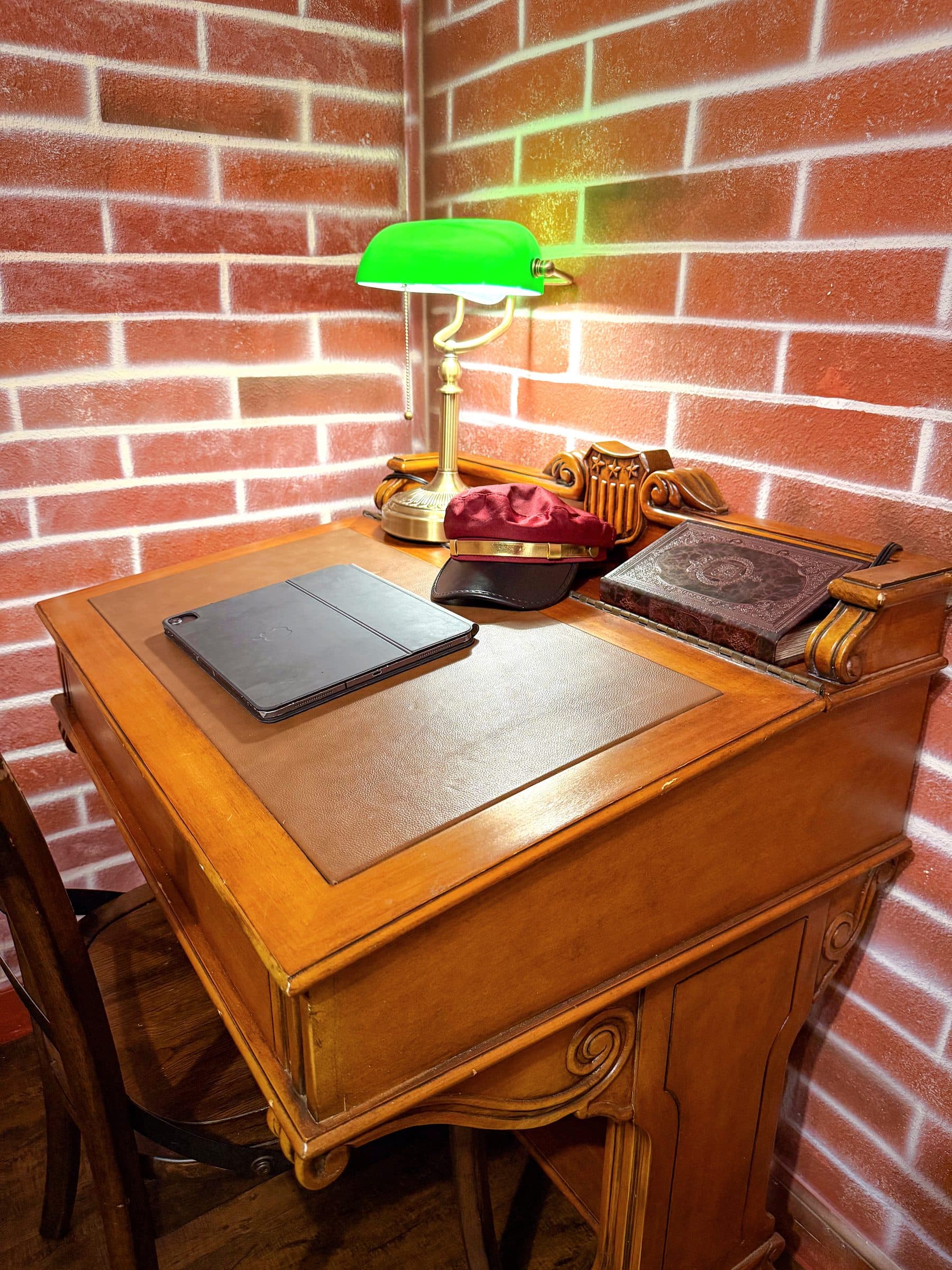 Overhead view of the antique desk: green glass lamp, leather-bound book, conduct