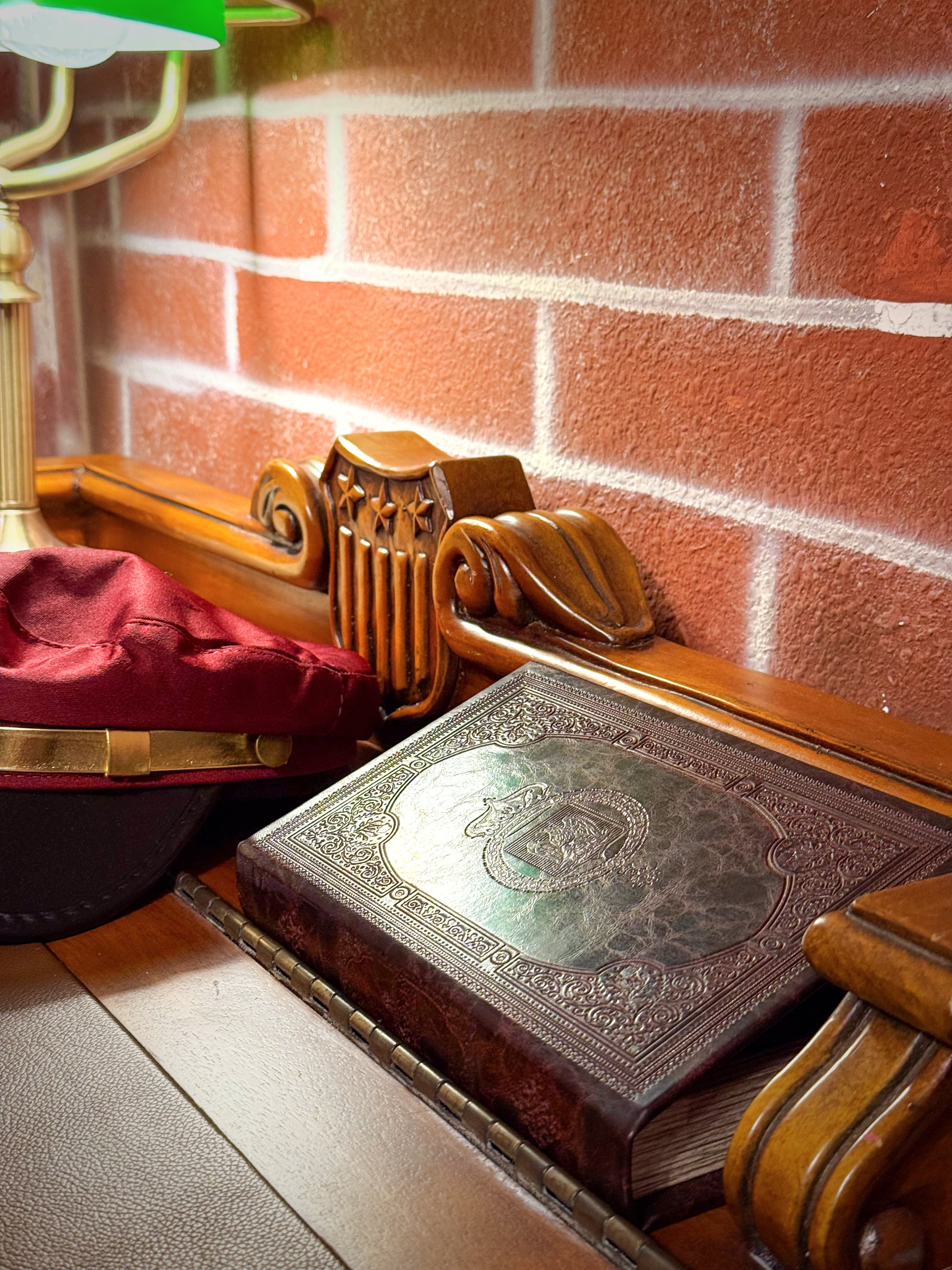 Green lamplight warming the brick, a crimson conductor's cap beside a carved oak