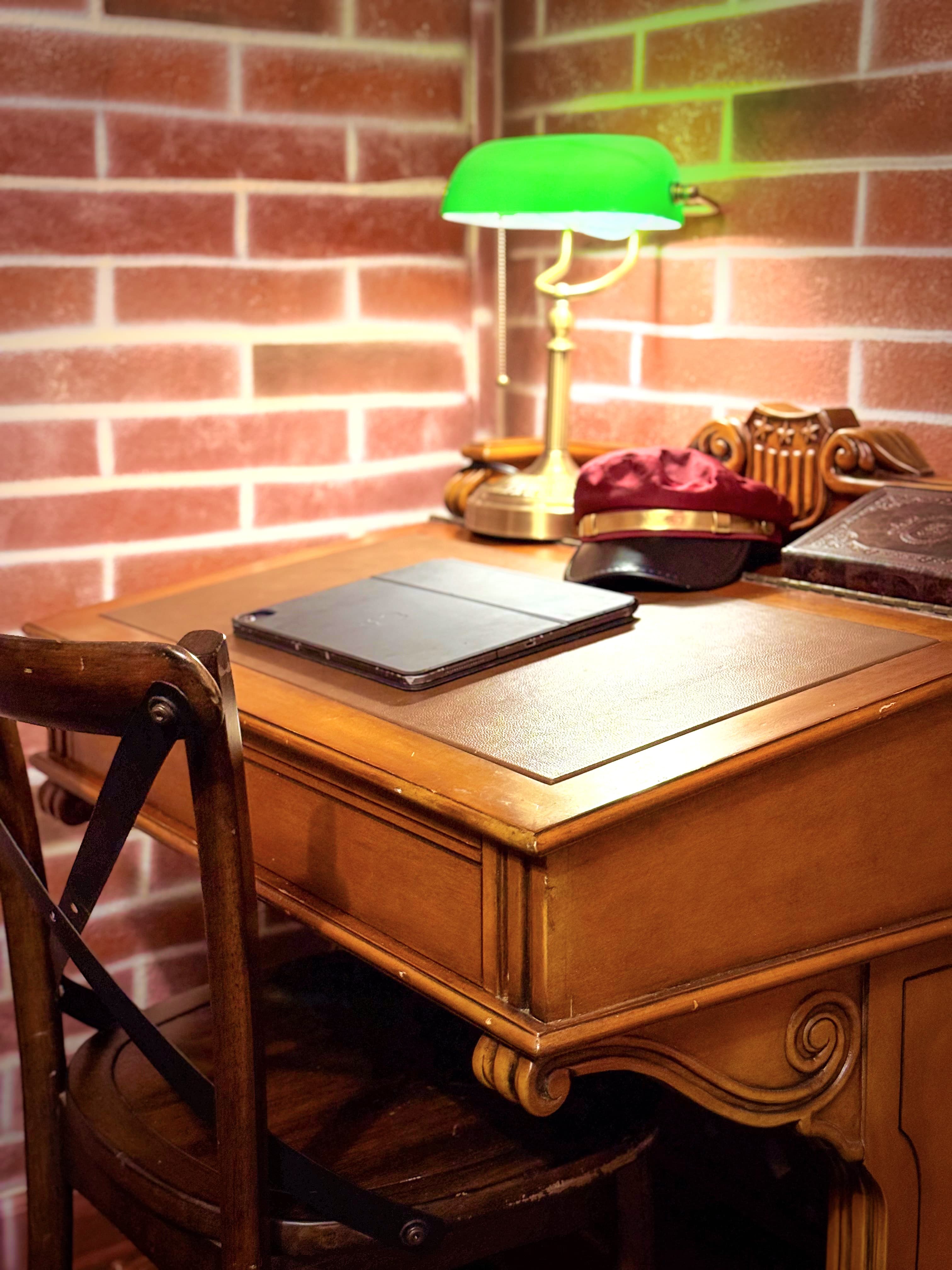Green banker's lamp, conductor's cap, a leather-bound journal on an 1800s House