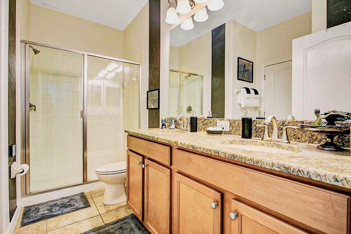Granite countertop, walk-in glass shower, and warm pendant lighting steps from t