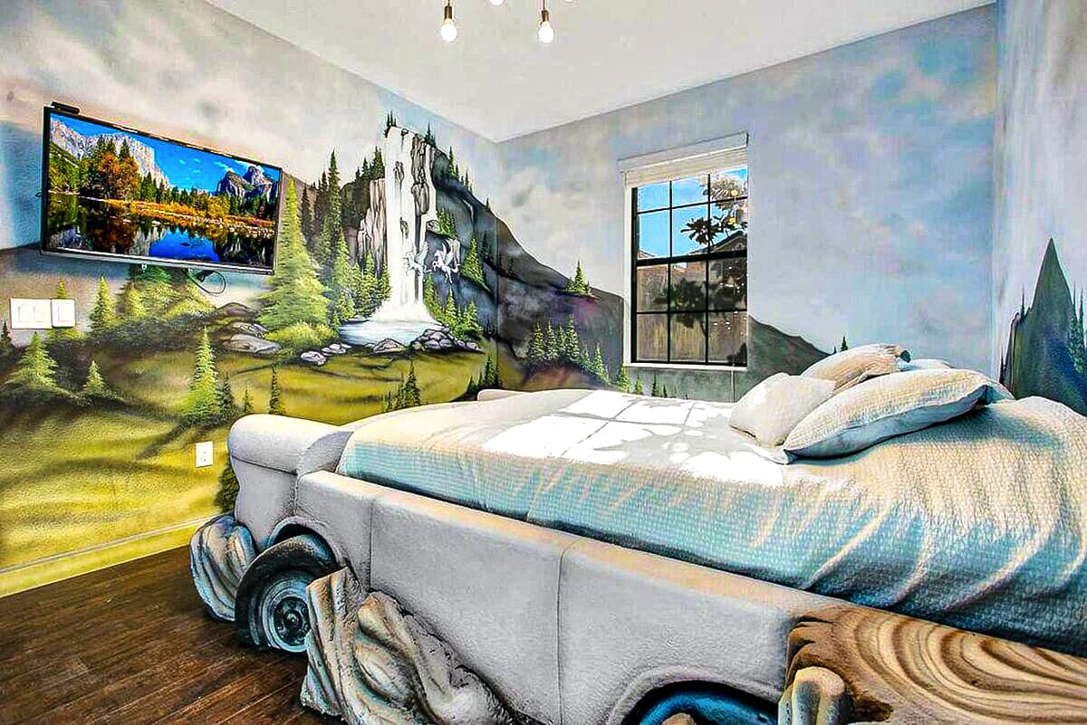 Painted waterfalls cascade down the wall behind the flying car bed — a blue owl,