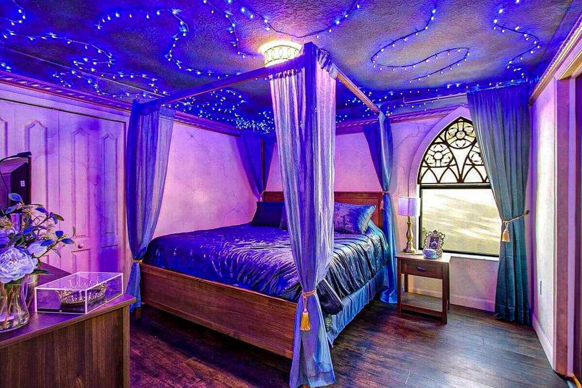 Constellation fairy lights spiral overhead, sheer blue canopy curtains drape a f