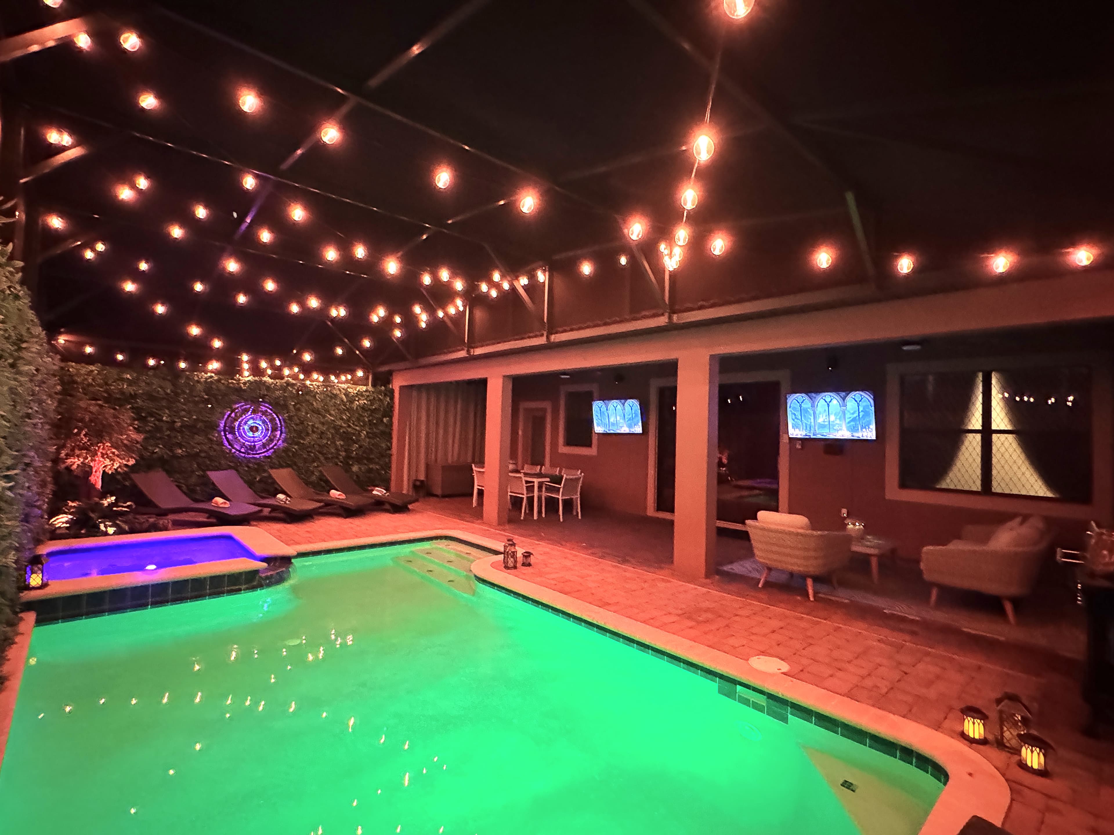 After dark, Edison string lights canopy the pool and a glowing sigil pulses on t