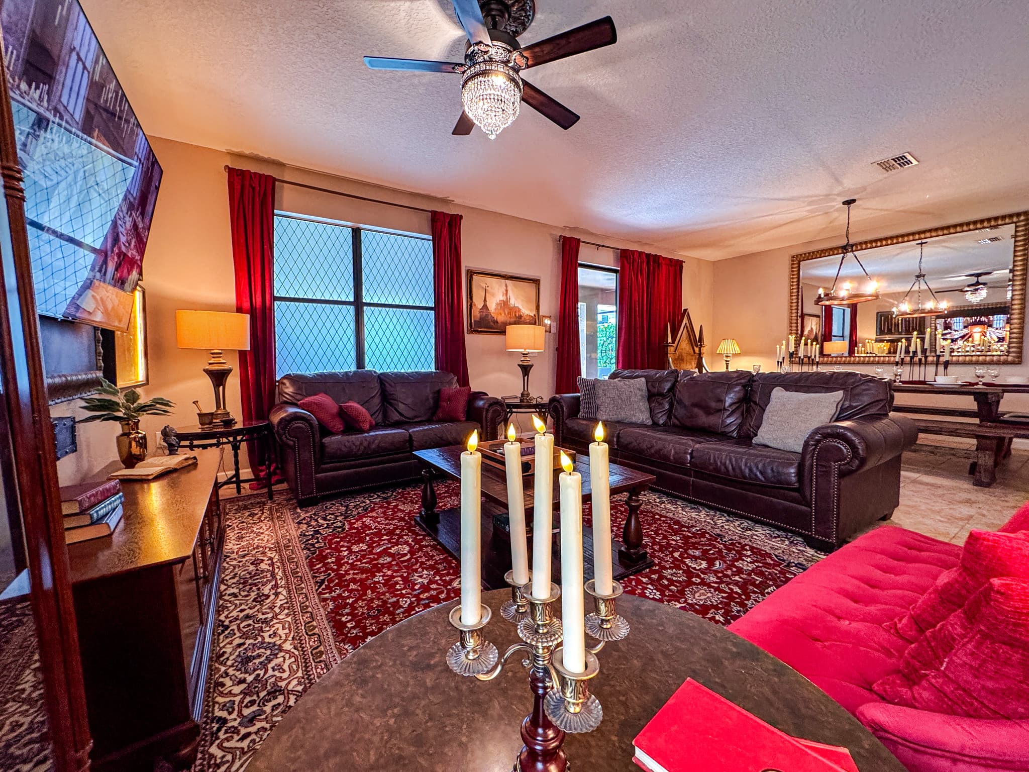 Candelabras flicker beside red velvet and deep leather, the 65-inch screen glows