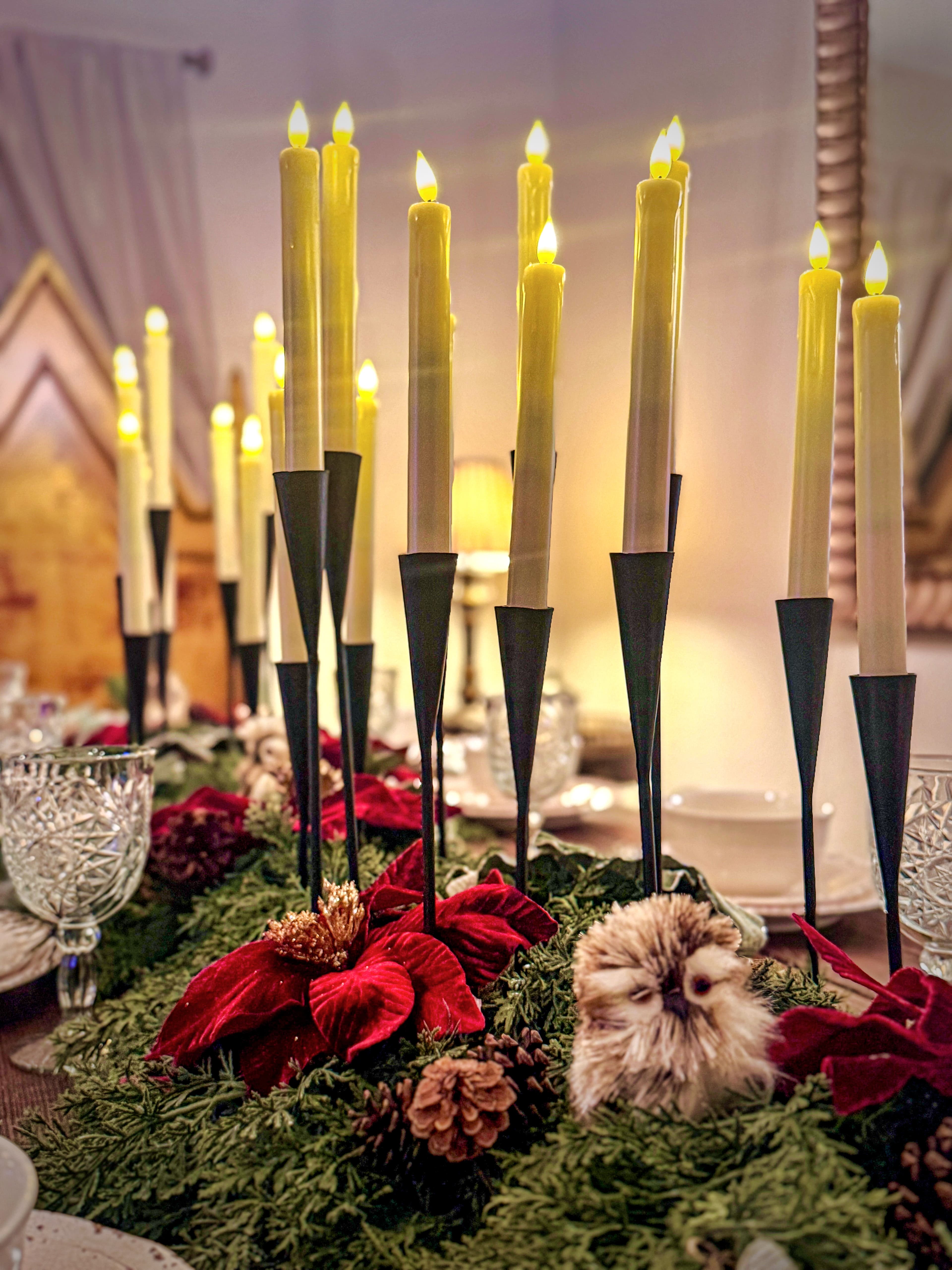 Taper candles rise from a nest of fresh greenery, red poinsettias, and a baby sn